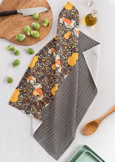 two pieces of fabric sitting on top of a cutting board next to a wooden spoon