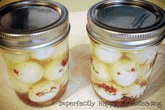 two jars filled with pickled onions on top of a table