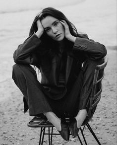 a black and white photo of a woman sitting on a chair with her hands behind her head