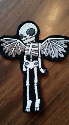 a skeleton with wings is sitting on a wooden table and it looks like he's holding something in his hand