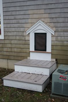 an air conditioner sitting on the side of a house next to a doghouse