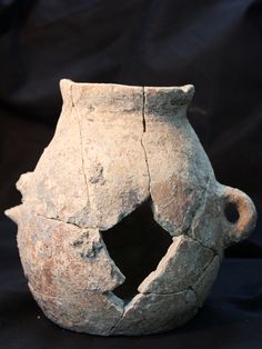 an old vase with holes in it on a black background