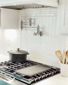 a stove top oven sitting inside of a kitchen next to a pot and spatula