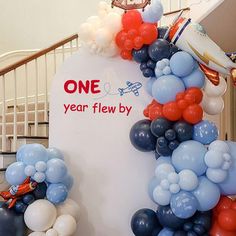 balloon arch with one year flew by sign and balloons on the ground in front of stairs