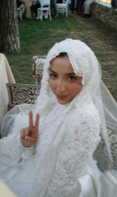 a woman wearing a veil and holding up the peace sign