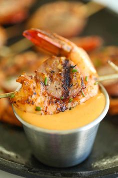 shrimp skewers in a small metal bowl with dipping sauce