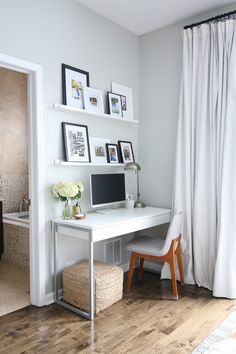 a white desk with a computer on top of it in front of a curtained window