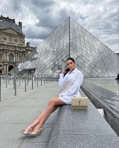 a woman sitting on a ledge in front of a pyramid