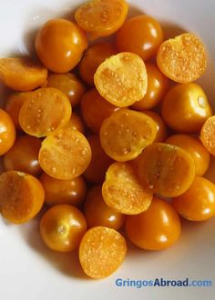 a white bowl filled with oranges on top of a table