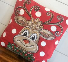 a red pillow with white polka dots and a cartoon reindeer on it's face