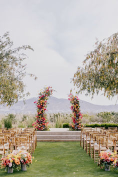 an outdoor ceremony set up with wooden chairs and flowers