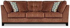 a brown couch with blue and green pillows on it's back end, sitting in front of a white background