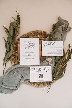 the wedding stationery is laid out on a woven wicker basket with greenery