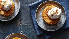 three plates with desserts on them sitting on top of a blue table cloth next to each other