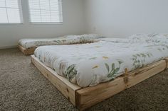 two beds in a room with carpeted flooring and white walls, one is made out of wood