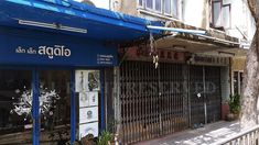 an empty street in front of a building with blue awnings on the windows