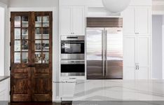 a kitchen with white cabinets and an open door leading to the dining room, which also has glass doors