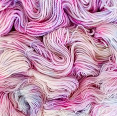 several skeins of yarn are stacked on top of each other in shades of pink and white