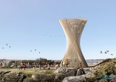 people are walking around in front of a tall tower with birds flying over the top