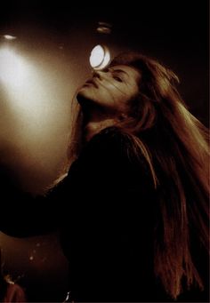 a woman with long hair standing in front of a light