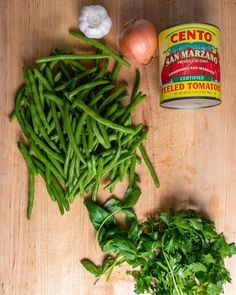 green beans, onions and garlic on a cutting board next to a can of san marrano