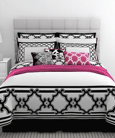 a white and black bed with pink accents