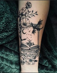 a woman's leg with an open book and flowers on it, reading the reader