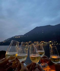 several glasses of wine are sitting on a table with people holding their hands in front of them