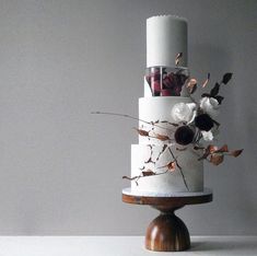 a three tiered white cake with flowers on it's side and the words havesomecakeuk birmingham, united kingdom