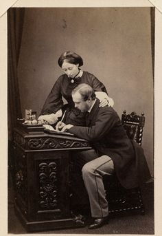 an old black and white photo of two people sitting at a desk writing on paper