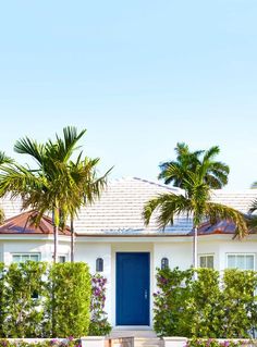 a white house with blue door and palm trees