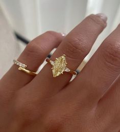 a woman's hand with a yellow diamond ring on it