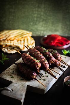 several skewered meats are sitting on a cutting board