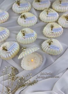 there are many seashells on the table with tags attached to them and some flowers