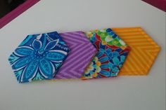 four folded napkins sitting on top of a white table next to an orange and blue flower