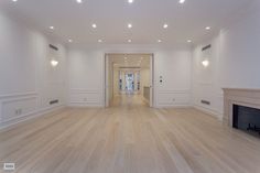 an empty living room with hard wood floors and white walls, along with a fireplace