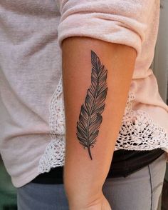 a woman's arm with a feather tattoo on the left side of her arm