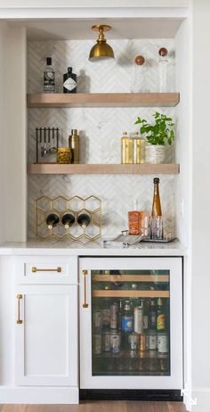 a kitchen with white cabinets and shelves filled with bottles, wine glasses and other items