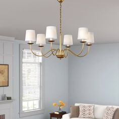 a chandelier hanging from the ceiling in a living room with blue walls and white furniture