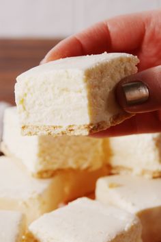 a hand holding a piece of white cake in it's middle, with other pieces on the side