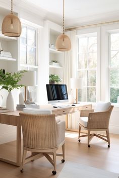 a home office with wicker chairs and a computer on a desk in front of two large windows