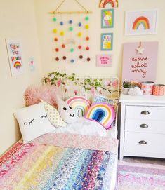 a bedroom with a rainbow quilt, pillows and pictures on the wall above the bed