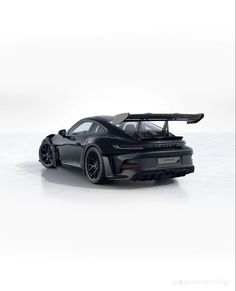 a black sports car with its hood down on a white surface, in the middle of an empty room