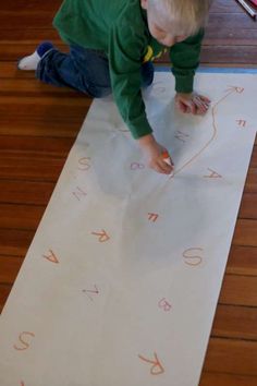 a little boy that is sitting on the floor with some scissors in his hand and writing