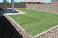 an empty backyard with grass and gravel