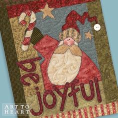 a quilted wall hanging with a santa clause on it's face and the words joy