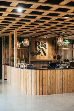 a wooden bar with lights hanging from it's ceiling and plants on the wall