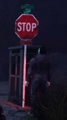 a man standing next to a stop sign at night