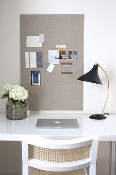 a laptop computer sitting on top of a white desk next to a vase with flowers