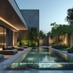 an outdoor swimming pool surrounded by greenery and lounge chairs at dusk with the lights on